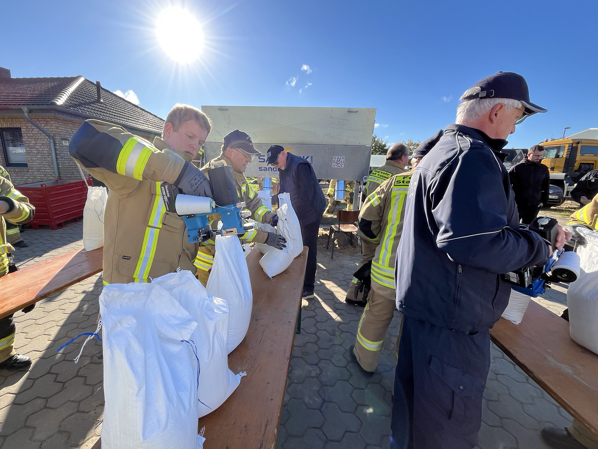 Feuerwehrleute vernähen und verpacken die fertigen Sandsäcke Feuerwehrleute vernähen und verpacken die fertigen Sandsäcke